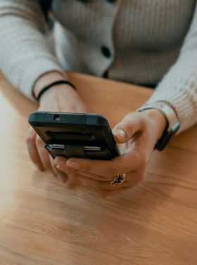 woman in white sweater holding black smartphone